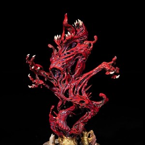 May include: A red, fleshy, and monstrous creature with multiple arms and sharp claws. The creature is standing on a black base with gold accents.