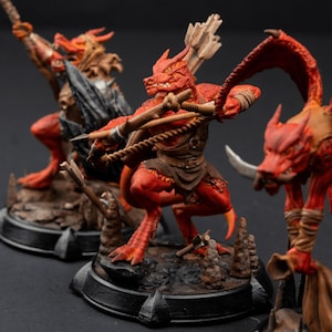 May include: Three red dragon miniatures with wings, tails, and horns. Each miniature is holding a bow and arrow and is posed in a fighting stance. The miniatures are painted in a realistic style with detailed features.