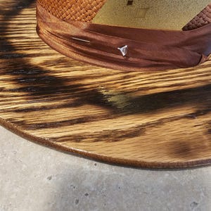 May include: A brown woven hat with a brown ribbon and a gold patch with the number "8" on it. The hat is sitting on a wooden base.