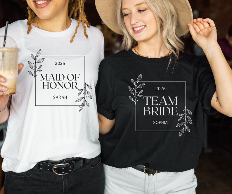 May include: Two white t-shirts with black text and floral designs. The first shirt says "Maid of Honour 2025 Sarah". The second shirt says "Team Bride 2025 Sophia".