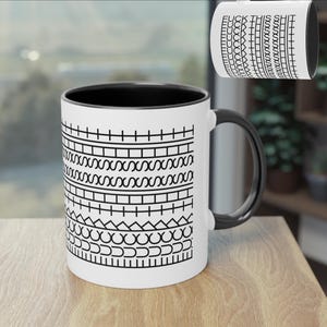 Könnte beinhalten: Weiße Keramiktasse mit schwarzem Innenraum und Griff. Die Tasse hat ein sich wiederholendes schwarz-weißes Muster aus verschiedenen geometrischen Formen und den Text "FUCK THIS" am Rand.