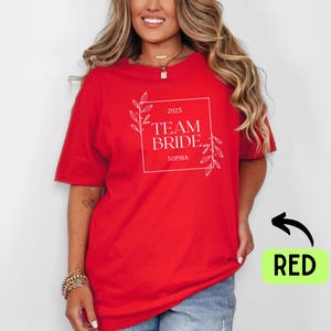 May include: Red t-shirt with white text that says "2025 Team Bride Sophia" with a floral design.