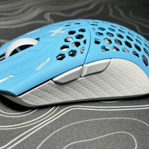 May include: A light blue gaming mouse with a honeycomb design on the top. The mouse has white and silver accents, including the scroll wheel and side buttons. The bottom section has a textured silver finish.