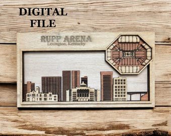 May include: Wooden laser-cut artwork featuring a cityscape and Rupp Arena in Lexington, Kentucky. The artwork includes the text "DIGITAL FILE" and "RUPP ARENA Lexington, Kentucky". The design is in shades of brown and beige.