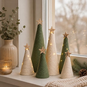 Könnte beinhalten: Eine Ansammlung von sechs kegelförmigen Dekobäumen, die mit grüner und cremefarbener Schnur umwickelt sind. Jeder Baum ist mit einem kleinen Holzstern gekrönt und mit warmweißen Lichterketten versehen, die um die Außenseite der Kegel gewickelt sind.