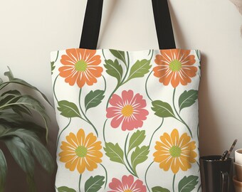 May include: A white tote bag with a floral pattern featuring orange, pink, and yellow flowers with green leaves and black handles. The bag is made of a durable fabric and is suitable for carrying groceries or other items.