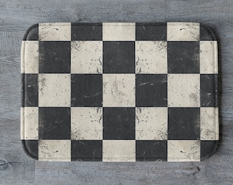 May include: A black and white checkered bath mat with a distressed, vintage look. The mat has a slightly textured surface and is made of a soft, absorbent material.