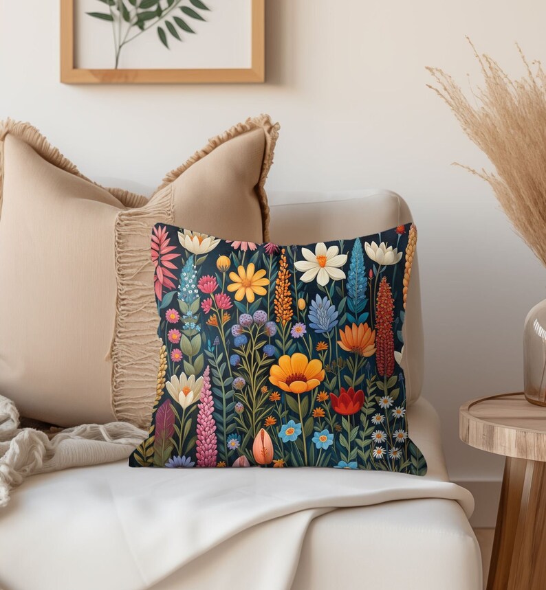K&ouml;nnte beinhalten: Ein dekoratives Kissen mit einem Blumenmuster. Das Kissen zeigt eine Vielzahl von bunten Blumen, darunter rosa, gelbe, blaue und rote, auf einem dunkelblauen Hintergrund.