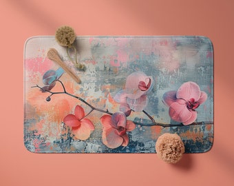 May include: A rectangular bath mat with a floral design. The mat features a light blue, gray, and pink abstract background with pink and red orchids.