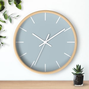 May include: A light blue round clock with white hands and white markings on a light wood frame.