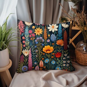 K&ouml;nnte beinhalten: Ein Dekokissen mit einem Blumenmuster. Das Kissen zeigt eine Vielzahl von bunten Blumen, darunter rote, gelbe, blaue und rosa Blumen, auf einem dunkelblauen Hintergrund.