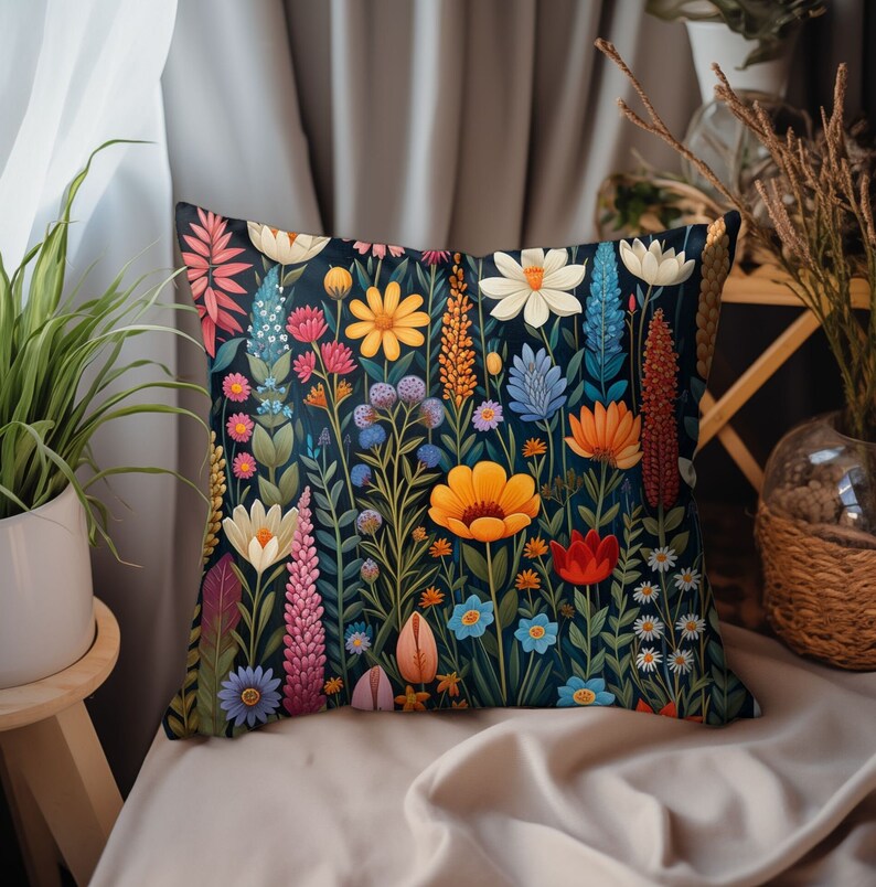 K&ouml;nnte beinhalten: Ein Dekokissen mit einem Blumenmuster. Das Kissen zeigt eine Vielzahl von bunten Blumen, darunter rote, gelbe, blaue und rosa Blumen, auf einem dunkelblauen Hintergrund.