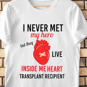 May include: White t-shirt with the text "I never met my hero but they live inside me heart transplant recipient" and a red heart with a bandage on it.