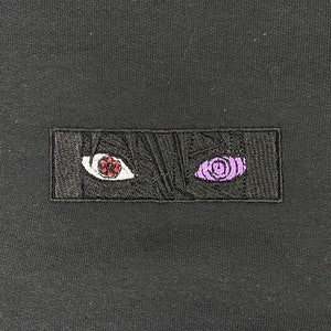 Pu&ograve; includere: Toppa ricamata nera con due occhi. L'occhio sinistro &egrave; rosso con una pupilla bianca e l'occhio destro &egrave; viola con un motivo a spirale.