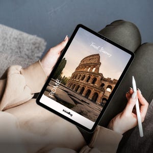 K&ouml;nnte beinhalten: Ein Tablet zeigt eine Reiseroute f&uuml;r Rom, Italien, mit dem Kolosseum. Auf dem Bildschirm stehen die Worte "Travel Itinerary" und "Rome", mit dem Logo "travelling". Ein wei&szlig;er Stift wird gehalten.