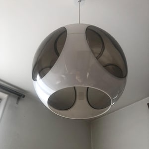 May include: A white and gray spherical pendant light fixture with a modern design. The light fixture has a white outer shell with three circular openings that reveal a gray inner shell.