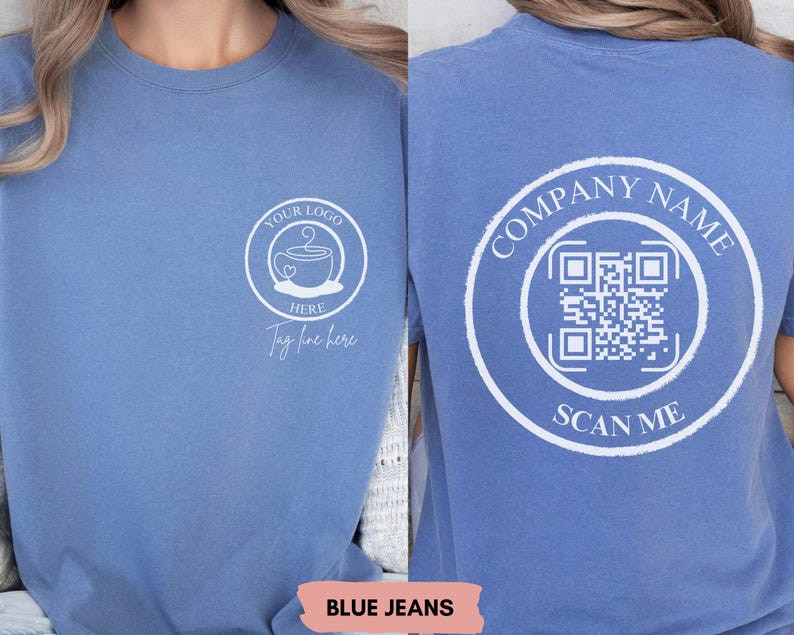 May include: A blue denim t-shirt with a white design on the front. The design includes a coffee cup with a heart and the text "Your Logo Here" and "Tag line here". The back of the shirt has a white circle with the text "Company Name" and a QR code with the text "Scan Me".