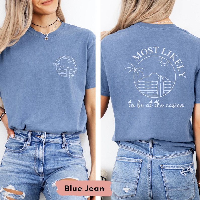 May include: A blue short-sleeved t-shirt with white graphic designs on the front and back. The front design says "Johnson Family Trip 2022" inside a circle. The back design says "Most Likely to be at the casino" with a surfboard and palm tree.