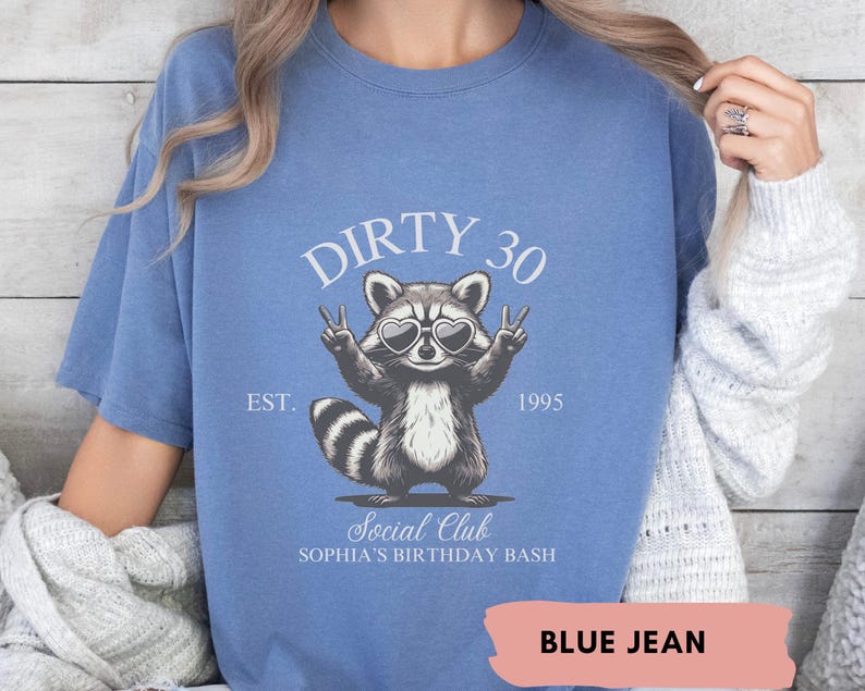 May include: A blue jean t-shirt with a raccoon wearing sunglasses and peace signs. The shirt says "Dirty 30 Est. 1995 Social Club Sophia's Birthday Bash".