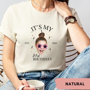 Puede incluir: Una camiseta blanca con el texto "It's My 21st Birthday" y un gr&aacute;fico de una mujer con gafas de sol. El texto "Est. 2004" tambi&eacute;n est&aacute; en la camiseta.
