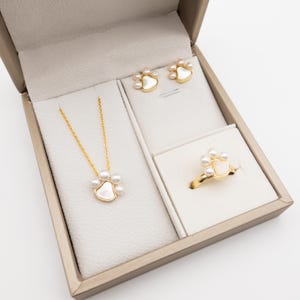 Op de afbeelding: Een set sieraden met een pootprintontwerp met parels. De set bevat een ketting, een ring en een paar oorbellen.