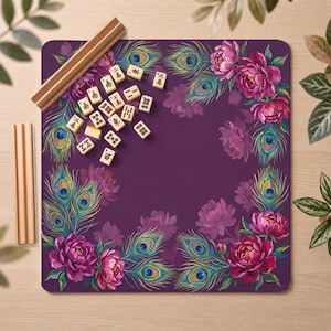 May include: A square purple mahjong mat featuring a border of vibrant pink peony flowers and iridescent peacock feathers. The mat is accompanied by a set of small, rectangular ivory-colored mahjong tiles with black symbols and two wooden tile racks.