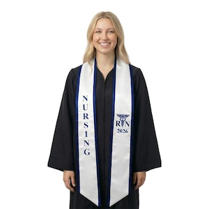 May include: A woman wearing a black graduation gown with a white and navy blue nursing sash. The sash has the word "NURSING" vertically printed on it, along with the Registered Nurse symbol and "RN 2026".