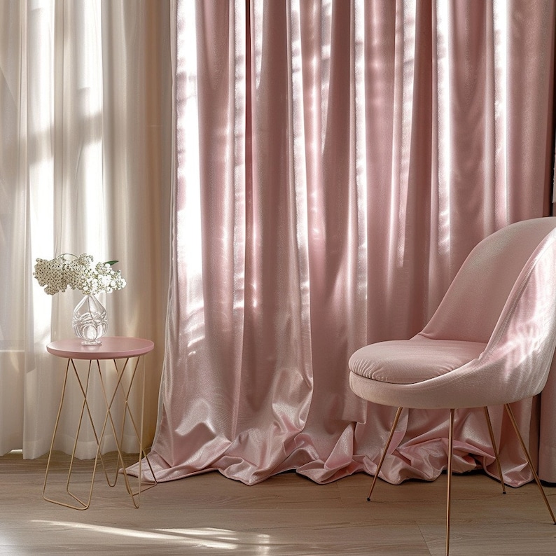 May include: A pink velvet chair with gold legs sits next to a gold metal side table with a pink top. The chair and table are in front of a pink velvet curtain.