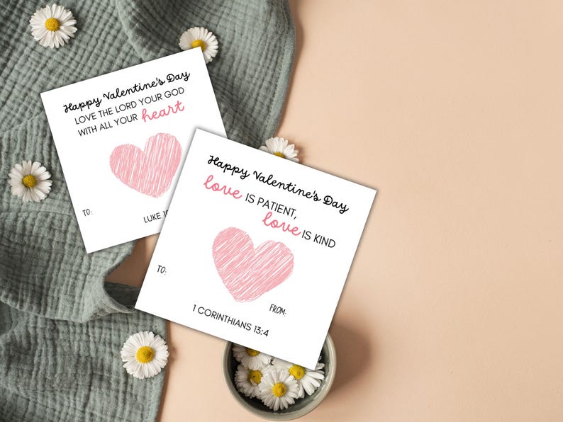 May include: Two white Valentine's Day cards with pink hearts and text that reads "Happy Valentine's Day Love the Lord your God with all your heart" and "Happy Valentine's Day love is patient, love is kind 1 Corinthians 13:4"