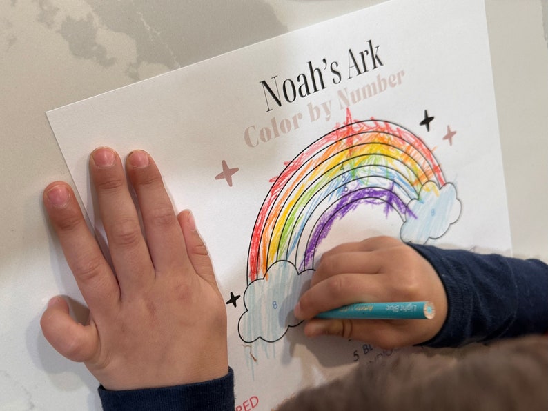 May include: A child colors a rainbow with crayons. The rainbow is labeled "Noah's Ark Color by Number".
