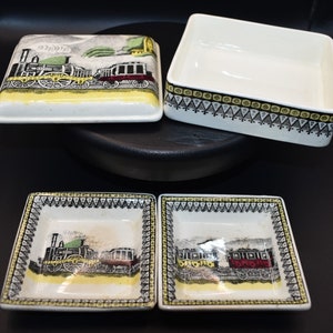 以下が含まれることがあります： 列車のデザインが施された、ヴィンテージのセラミック食器セット。セットには、蓋付きの正方形の皿、正方形のオープン皿、2つの小さな正方形の皿が含まれます。皿には、黒、黄、赤の列車のイラストが描かれています。