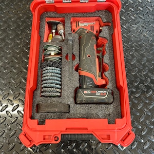 May include: A red tool case with a clear lid, containing a cordless power tool and various attachments. The tool is black and red, with a black handle. The case is on a diamond plate surface.