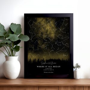 Könnte beinhalten: Ein gerahmter Sternenhimmel-Druck mit dunklem Nachthimmel, goldenen Nebelwolken, Sternbildern und einer Waldsilhouette. Der Text lautet: Sophie & Oliver, WHERE IT ALL BEGAN, 19 March 2024, 55.9533° N, 3.1883° W, Written in the Stars.