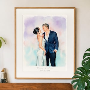 Op de afbeelding: Een ingelijst aquarelportret van een koppel dat samen staat. De persoon links draagt een witte jurk en de persoon rechts een donkerblauw pak. Onder de figuren staat de tekst Olivia & Jacob en JUNE 27, 2026.