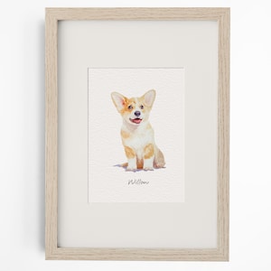 May include: A framed watercolour print featuring a tan and white Corgi puppy sitting down. The dog has large ears, a black nose, and an open mouth. Below the illustration, the name Willow is written in black cursive script on a white background.