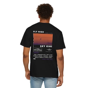 May include: Black t-shirt with a graphic print of a plane flying over a sunset with the text "FLY HIGH" and "SKY KING". The text below the graphic reads "JUST A BROKEN GUY, GOT A FEW SCREWS LOOSE, I GUESS... NEVER REALLY KNEW IT UNTIL NOW..."