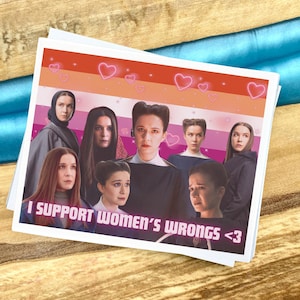 以下が含まれることがあります： レズビアンのプライドフラッグと女性のグループが描かれた正方形のステッカー。「I SUPPORT WOMEN'S WRONGS <3」というテキストが白で印刷されています。ピンクのハートの輪郭が上部に散らばっています。