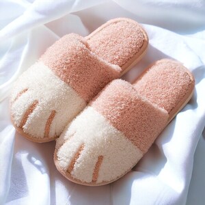 Pink plush slippers designed like cat paws, soft and warm for indoor use.
