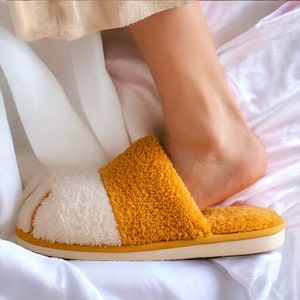 Yellow plush slippers designed like cat paws, soft and warm for indoor use.