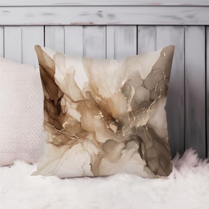 May include: A square throw pillow featuring an abstract alcohol ink design in shades of cream, beige, taupe, and dark brown. The pattern displays fluid, swirling organic shapes with thin, delicate gold-colored veins running throughout the surface.