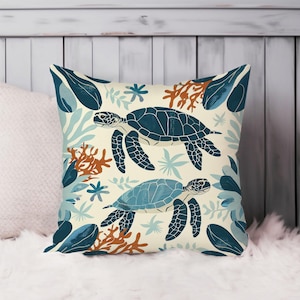 May include: A cream-colored throw pillow with a repeating pattern of blue and green sea turtles swimming among coral and seaweed.