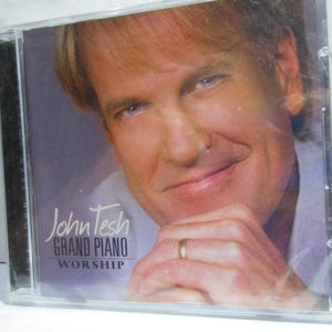 May include: A CD case with a photo of John Tesh on the front. The title of the album is "Grand Piano Worship".