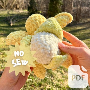 Può includere: Un fiore all'uncinetto con petali gialli e verdi e un centro bianco. Il fiore è tenuto in una mano e il testo "NO SEW" è visibile su una stella gialla. Il testo "PDF" è visibile su un rettangolo bianco.