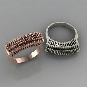 May include: Two rings with a unique design. The ring on the left is rose gold and the ring on the right is silver. Both rings have a row of small, vertical bars that create a textured look.
