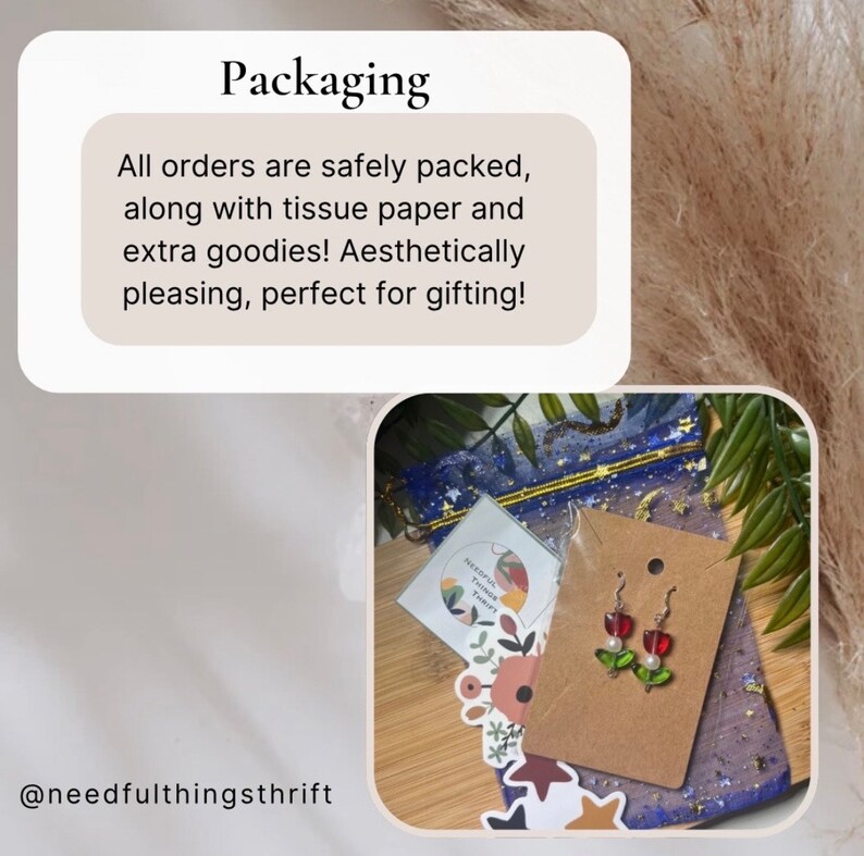 May include: Aesthetic packaging with tissue paper and extra goodies. The image includes a pair of red apple earrings with green leaves and white pearls. The packaging also includes a small card and a blue mesh bag.