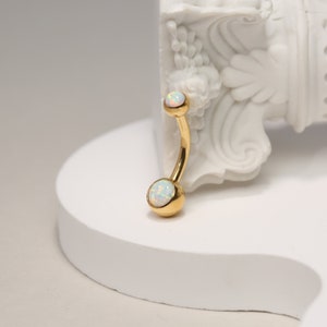 May include: Gold belly button ring with two white opal stones.