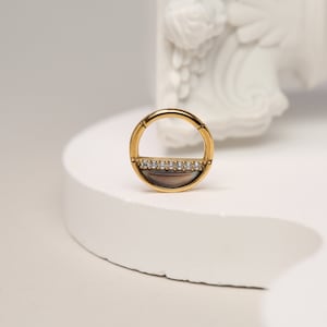 Puede incluir: Pendiente de aro de oro con una fila de piedras de circonita cúbica transparentes engastadas en un diseño de medio círculo.