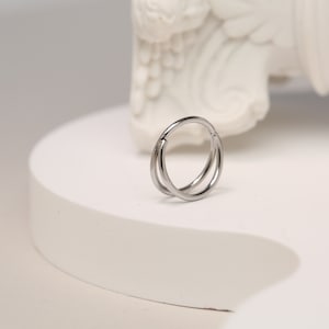 May include: A silver double hoop earring with a hinged closure.