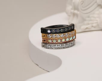 May include: Four hoop earrings with a row of clear cubic zirconia stones. The hoops are stacked on top of each other, with the top hoop being black, the second hoop being gold, the third hoop being rose gold, and the bottom hoop being silver.