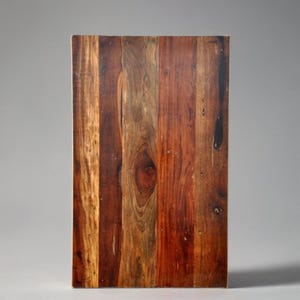 May include: A rectangular wooden surface with a rich, natural wood grain pattern. The surface is composed of vertical planks in varying shades of brown, red, and tan. The wood grain features knots and unique patterns.